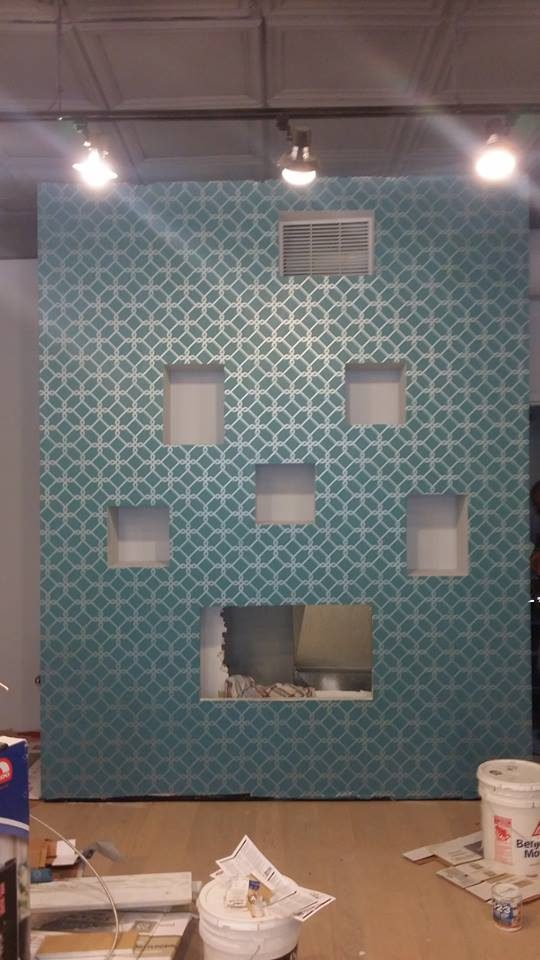 The same wall finished in a patterned deep-teal, niches picked out in a pale tone.