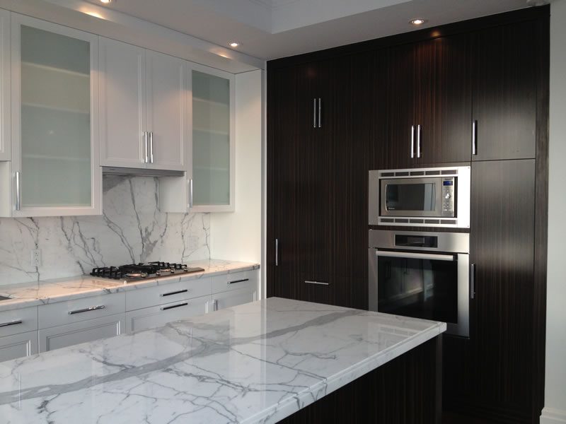 A dark kitchen with marble surfaces and painted joinery.